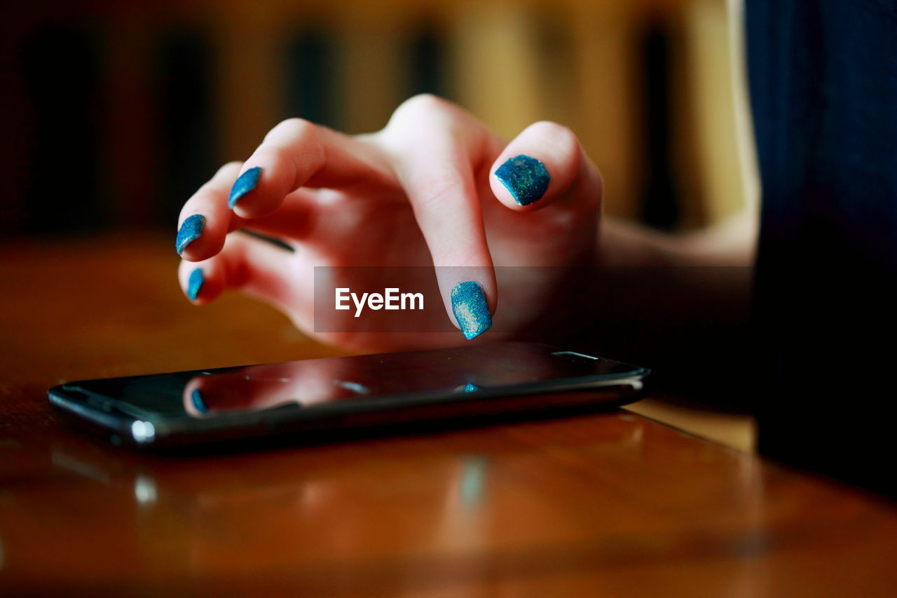 Cropped image of woman using phone at table