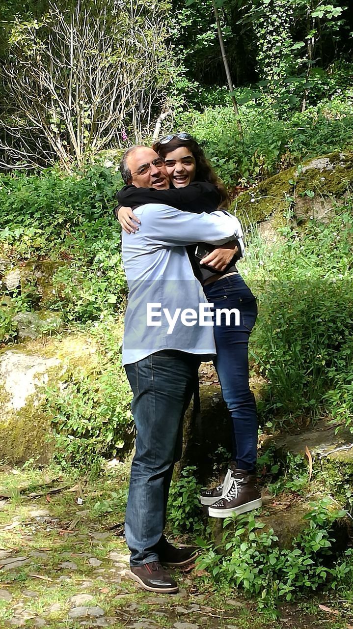 Portrait of happy father embracing daughter in park