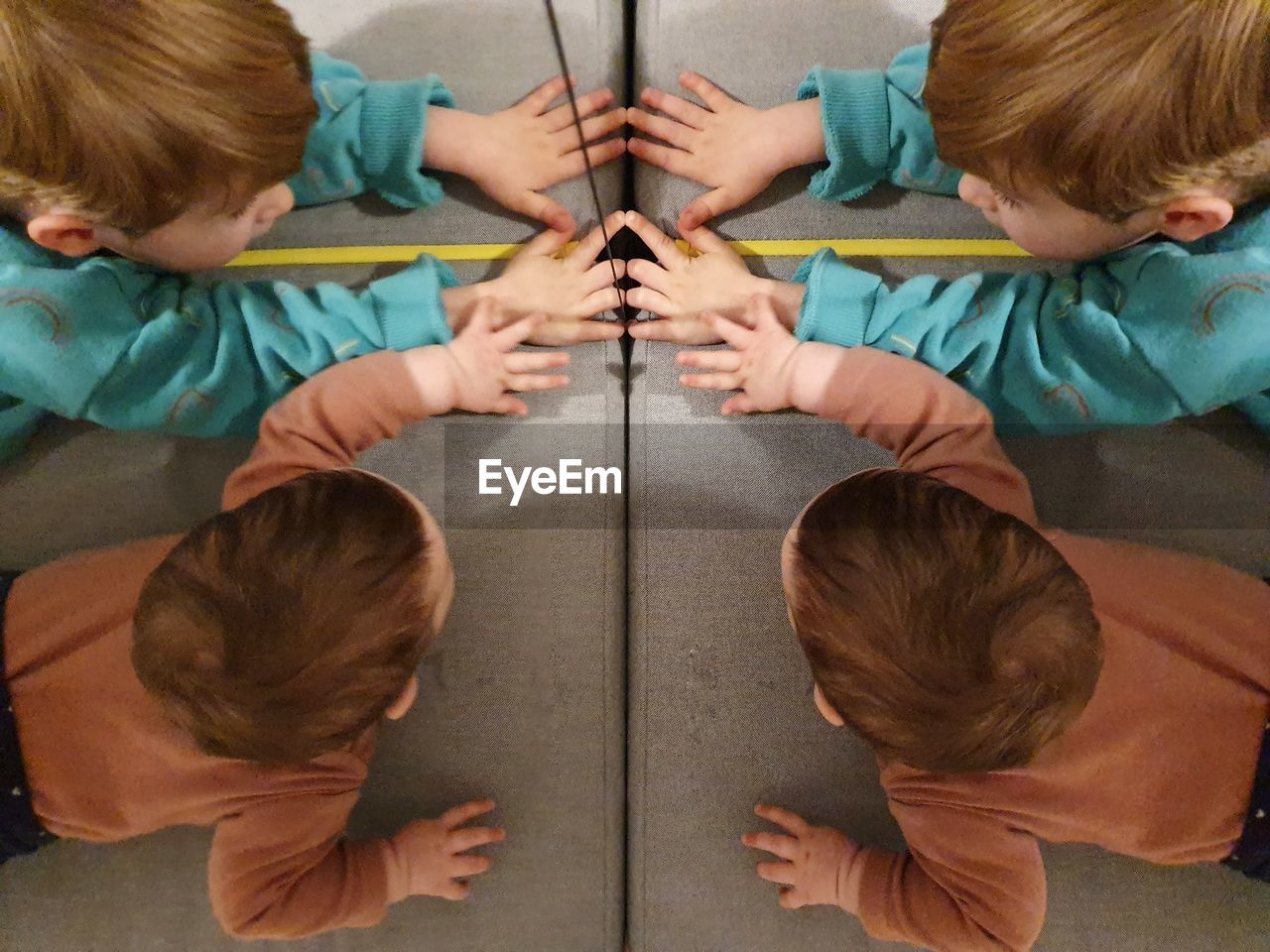 High angle view of siblings reflecting on glass 