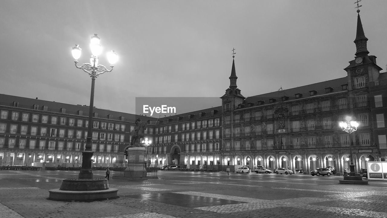 Illuminated street lights against buildings in city at night