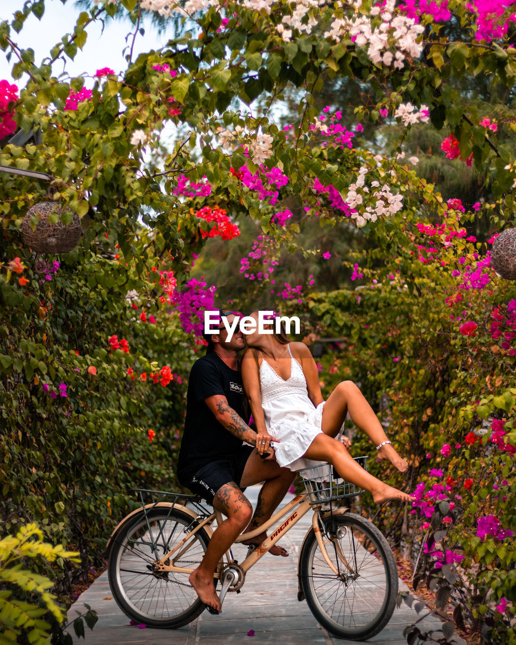 Romantic couple riding a bicycle surrounded by flowers