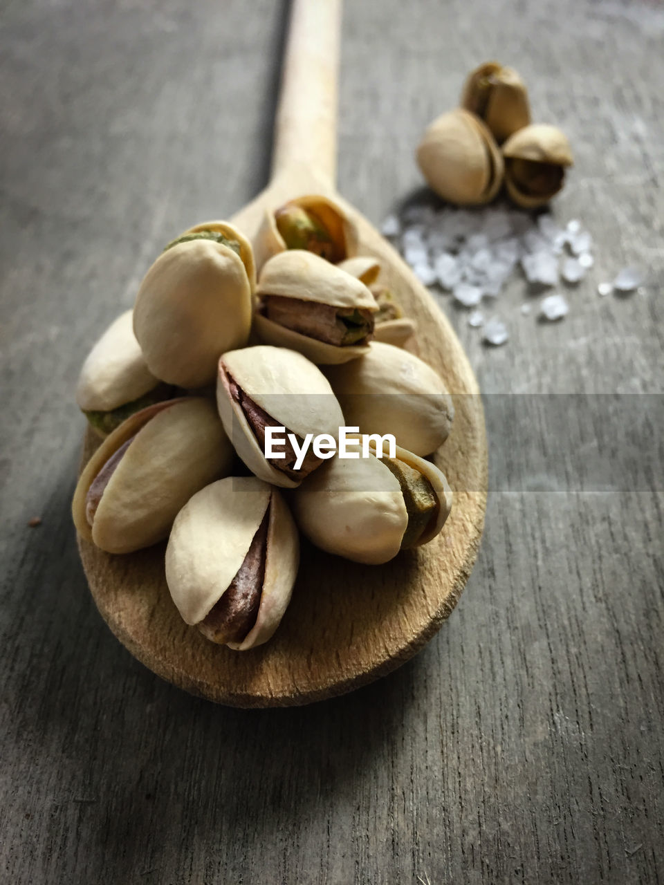 Close-up of pistachios on wooden spoon