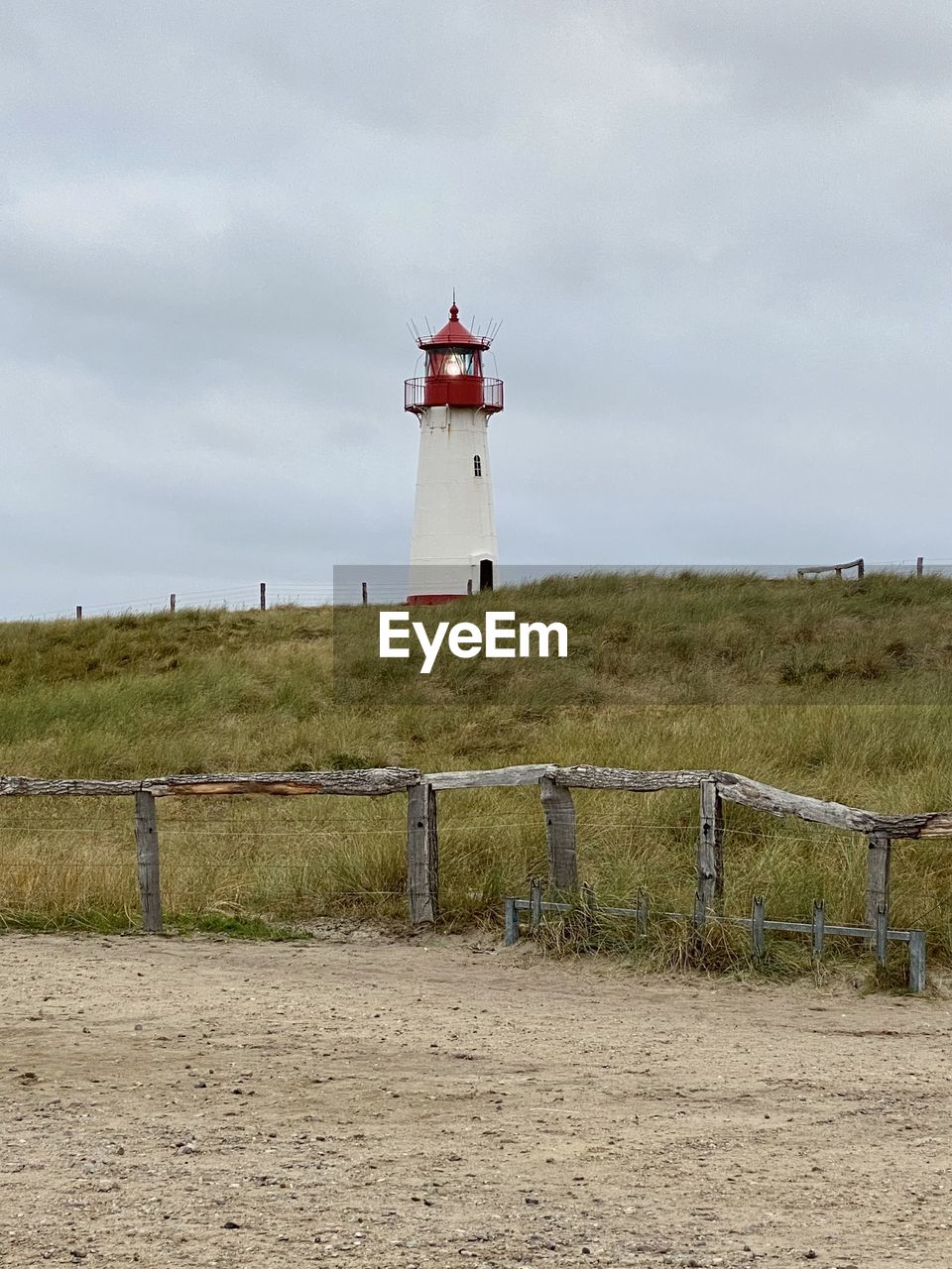 Lighthouse on field against sky