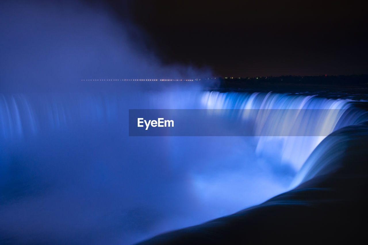 Scenic view of waterfall against sky at night