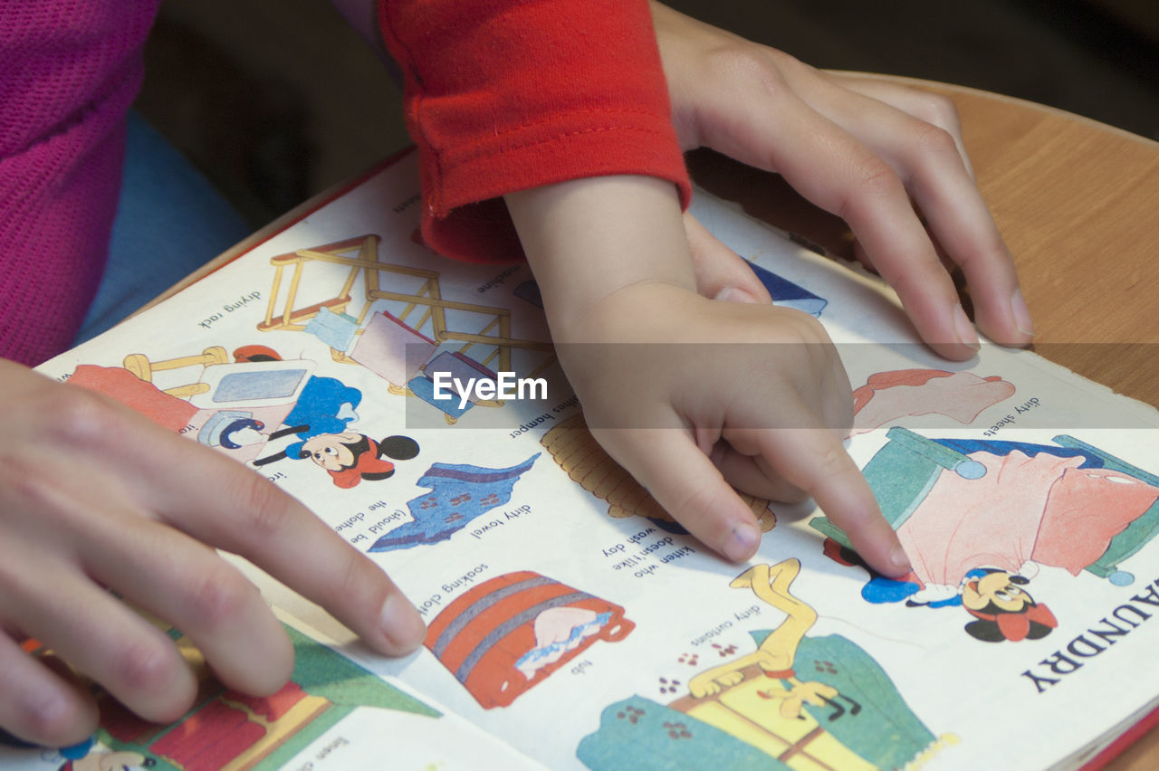 MIDSECTION OF CHILD HOLDING PAPER WITH TEXT