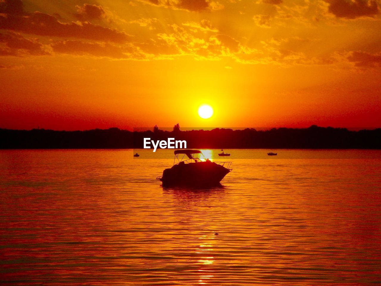 Silhouette boat in sea against orange sky