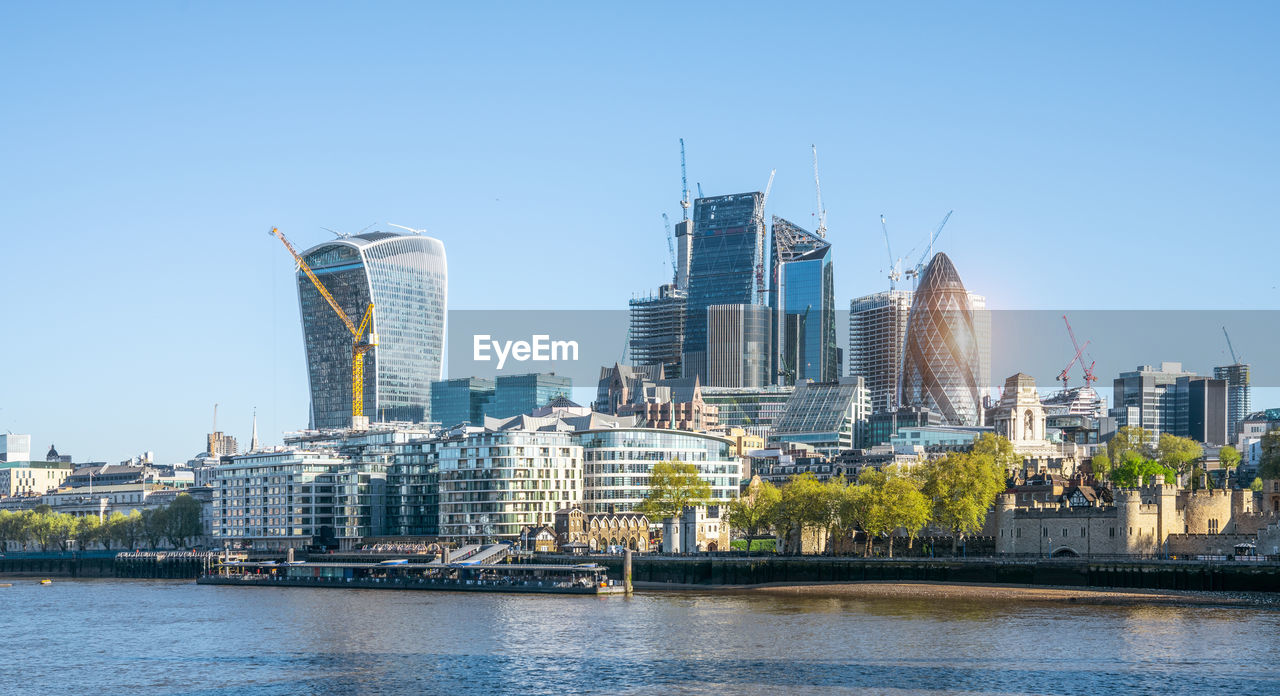 BUILDINGS BY RIVER AGAINST CLEAR SKY