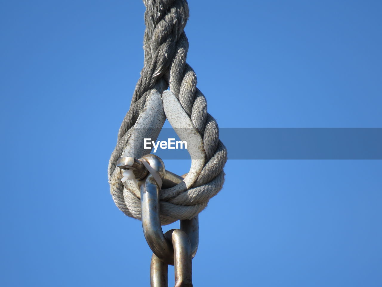 Low angle view of rope with hook against clear sky