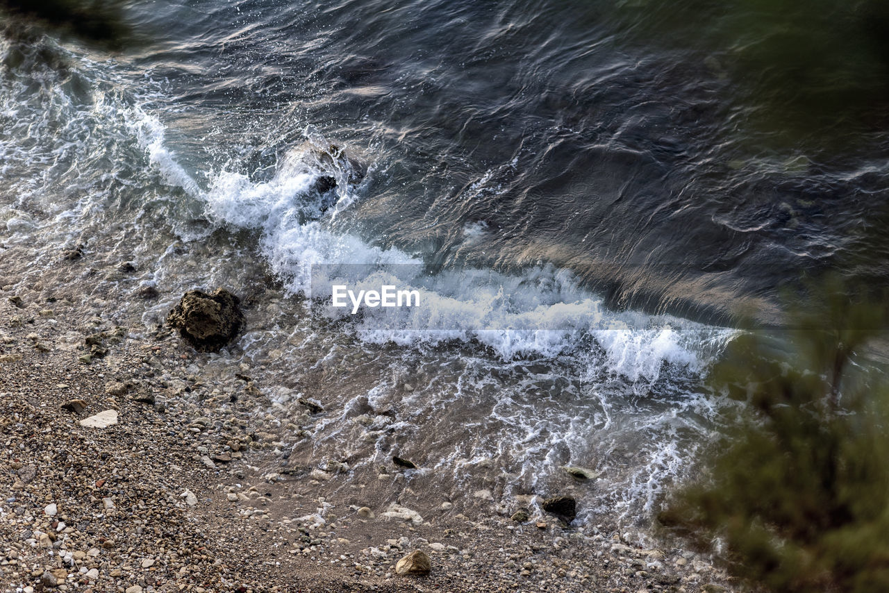 HIGH ANGLE VIEW OF WATER FLOWING OVER ROCKS