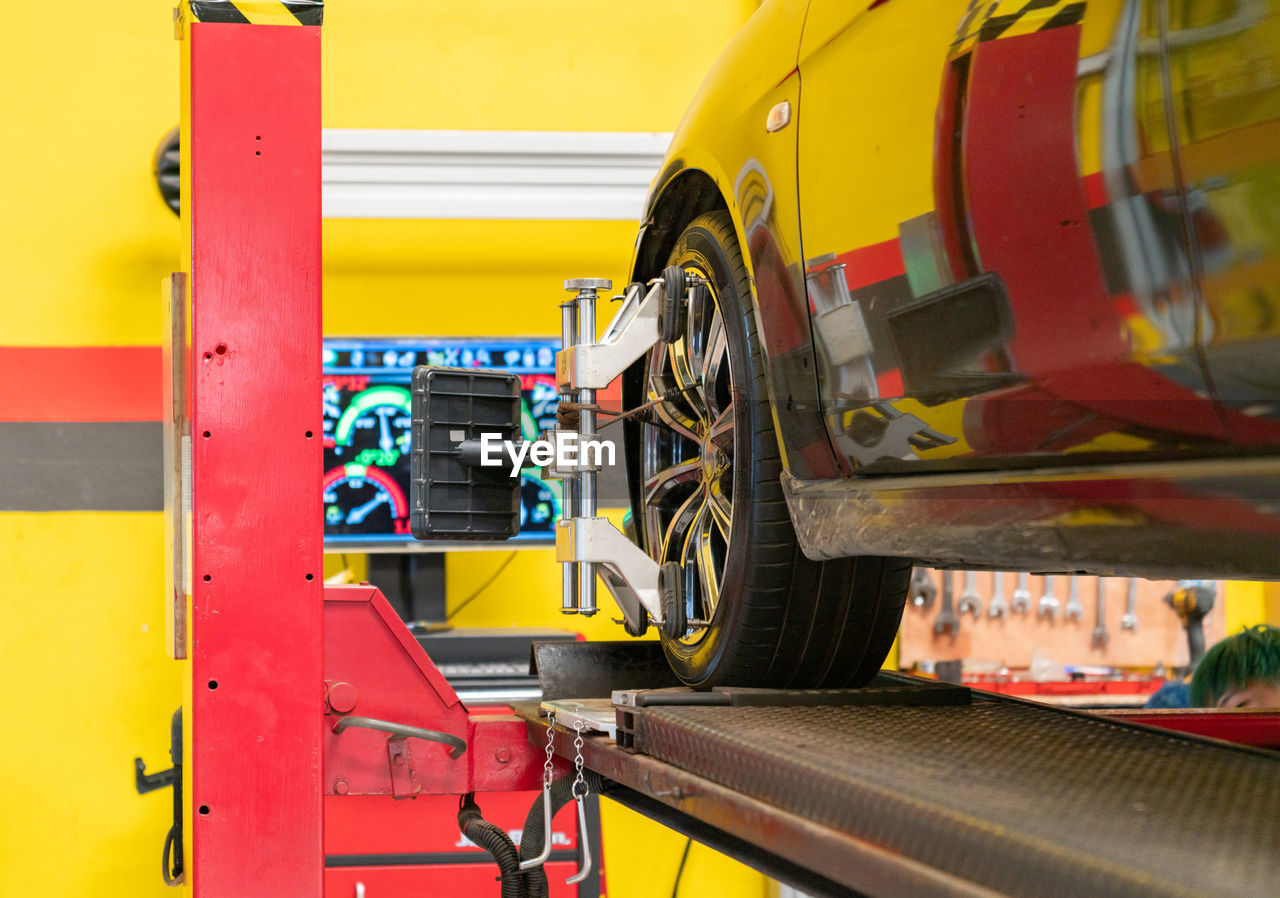 Car mechanic installing sensor during wheel alignment adjustment at repair service station