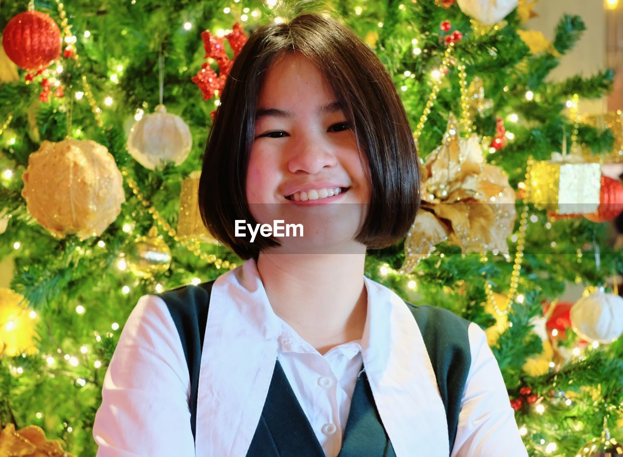 Portrait of girl standing against christmas tree