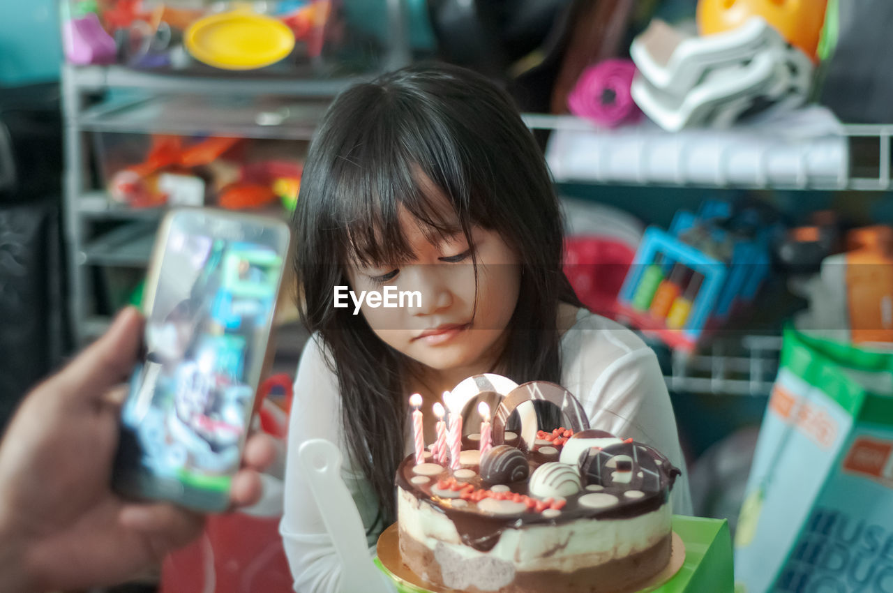 Close-up of cute girl sitting by cake at home