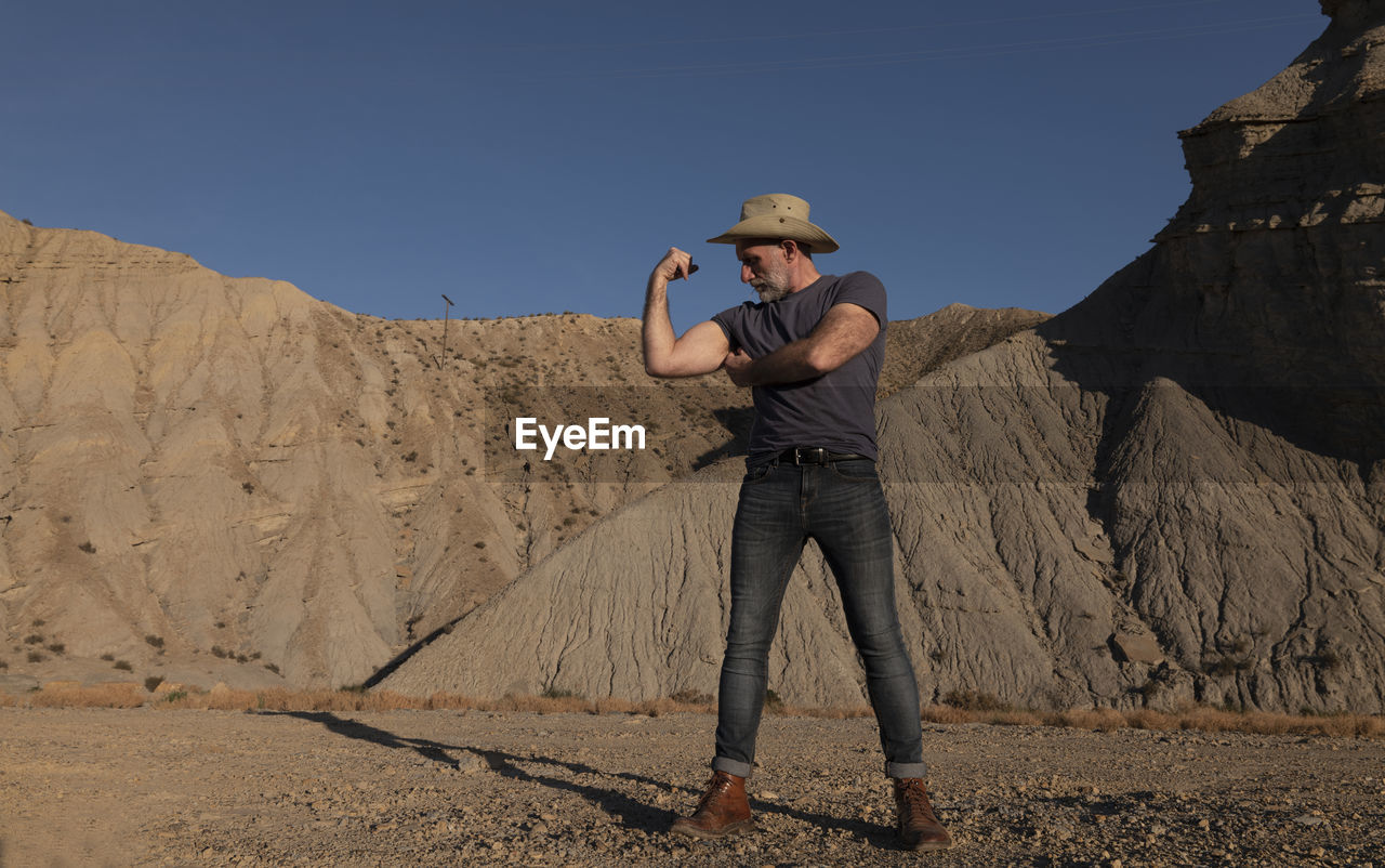 Adult man in cowboy hat on desert against mountain. almeria, spain