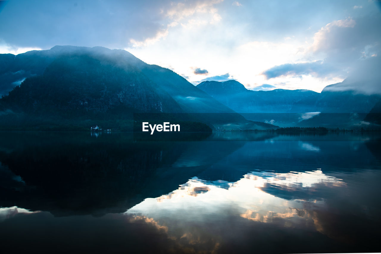 Scenic view of lake by mountains against sky