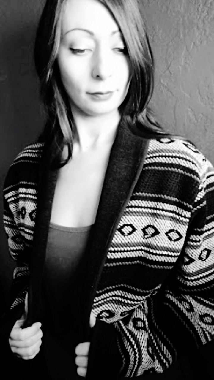 Young woman looking down while standing against wall