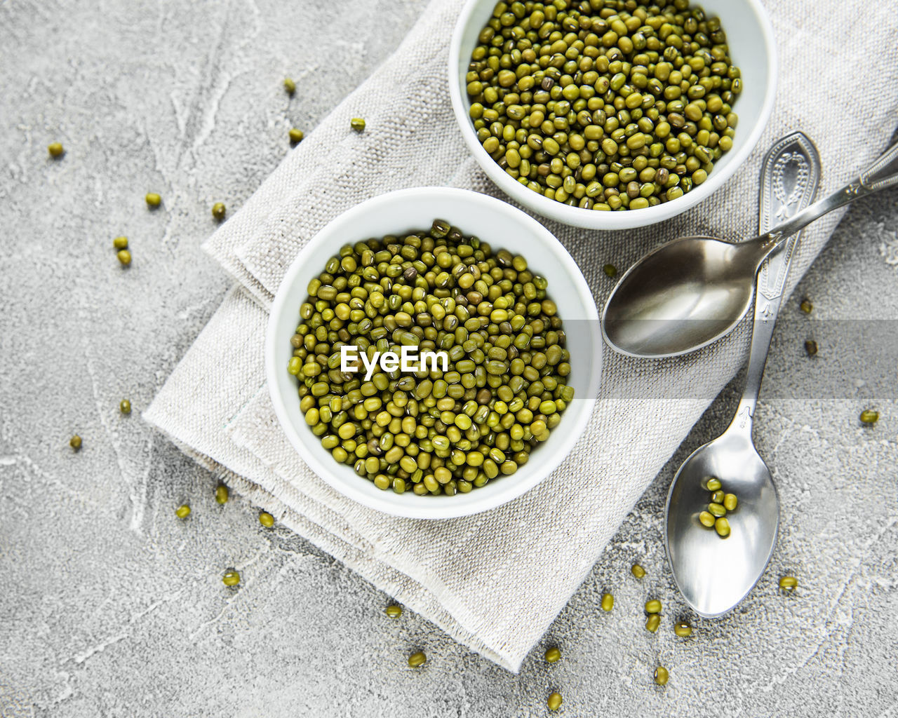 Raw mung beans in the bowls on a grey concrete background