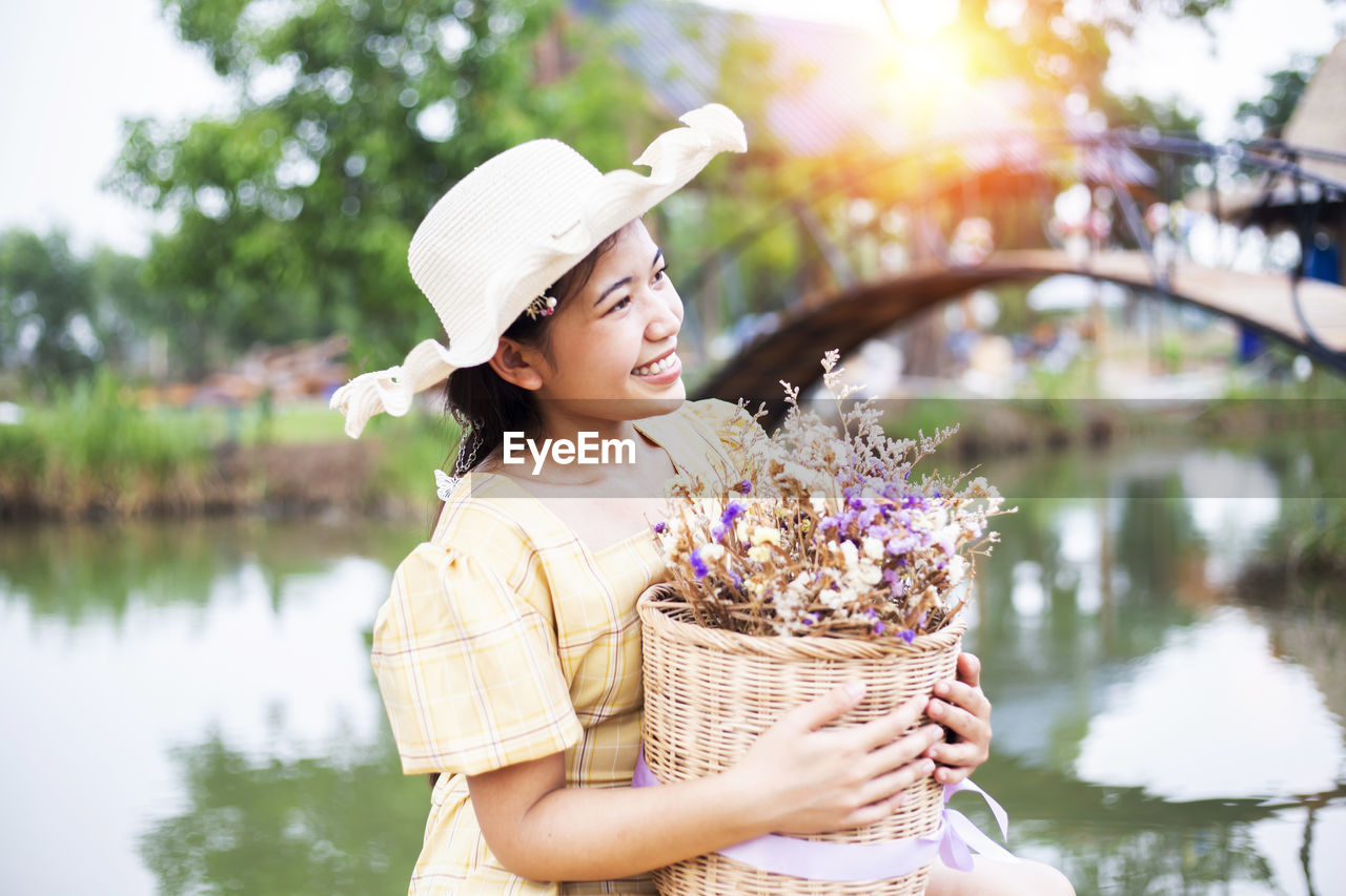 Close-up of woman holding flowers while sitting against lake