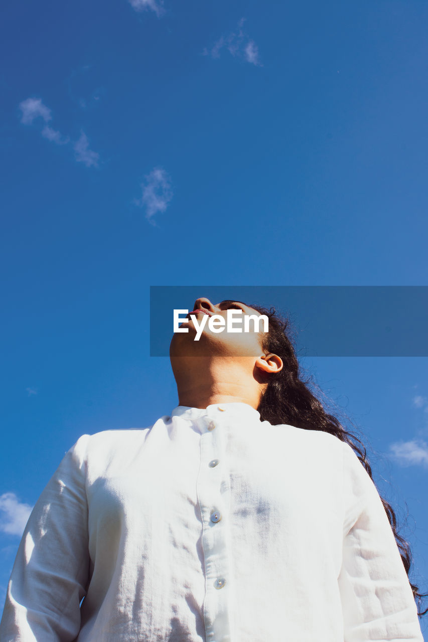 Low angle view of woman looking at blue sky