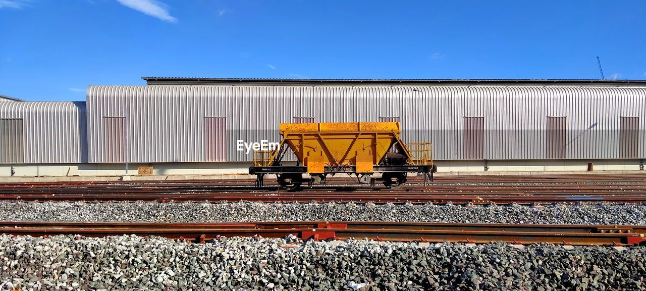 TRAIN ON RAILROAD TRACK AGAINST SKY