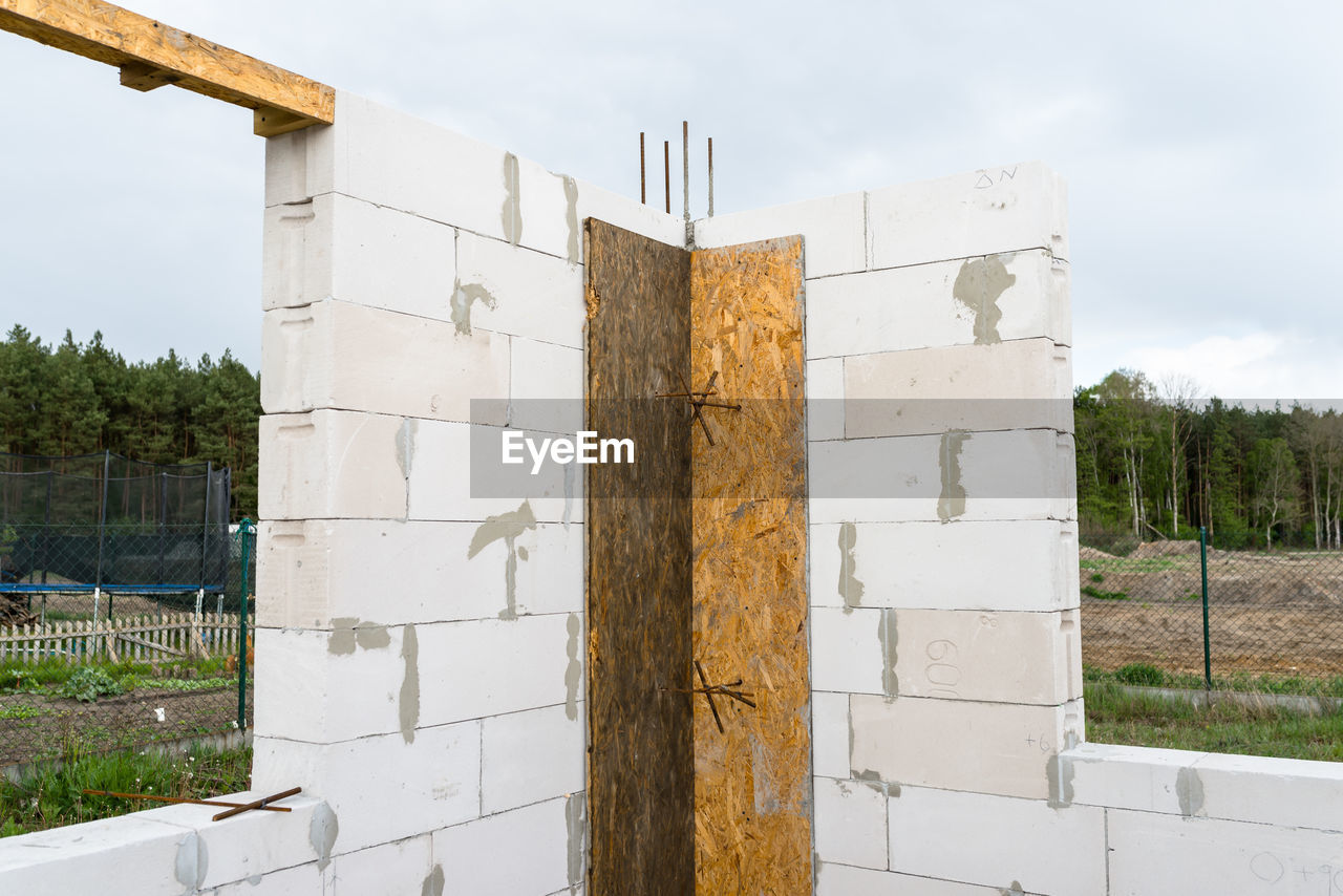 The walls of a house built of white brick with reinforced concrete pillars at the end of which