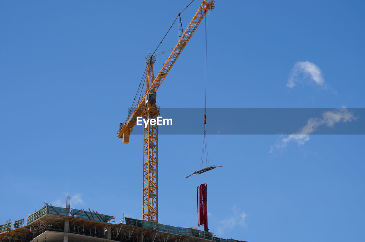 LOW ANGLE VIEW OF CRANES AT CONSTRUCTION SITE AGAINST SKY