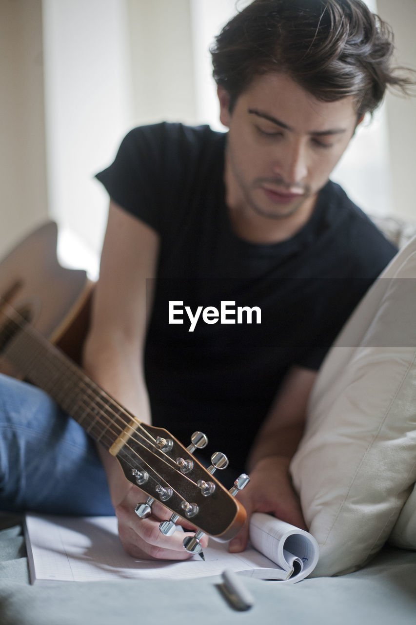 Young musician writing songs on an acoustic guitar