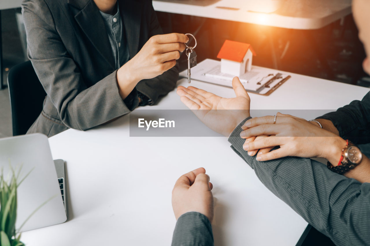 High angle view of real estate agent giving keys to customer on table