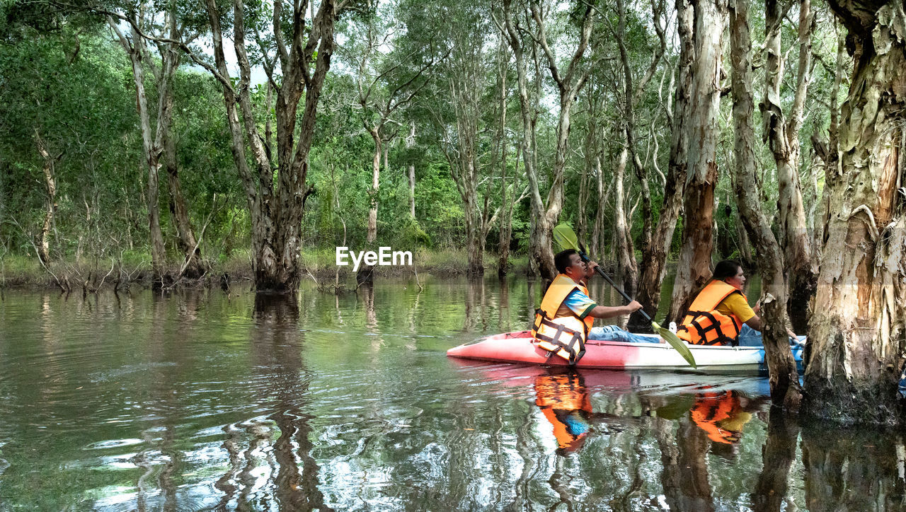 PEOPLE SITTING ON BOAT AGAINST TREES