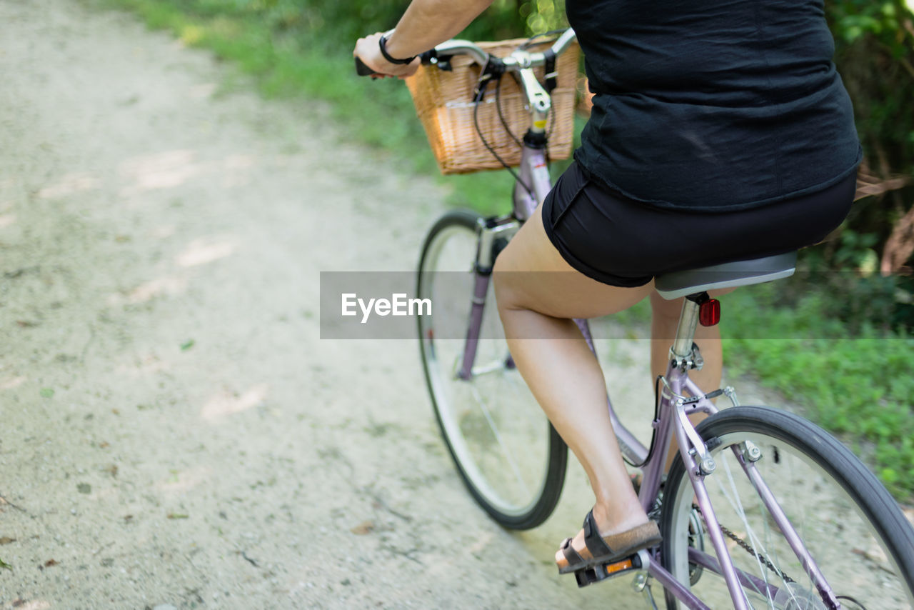 Low section of woman riding bicycle on road