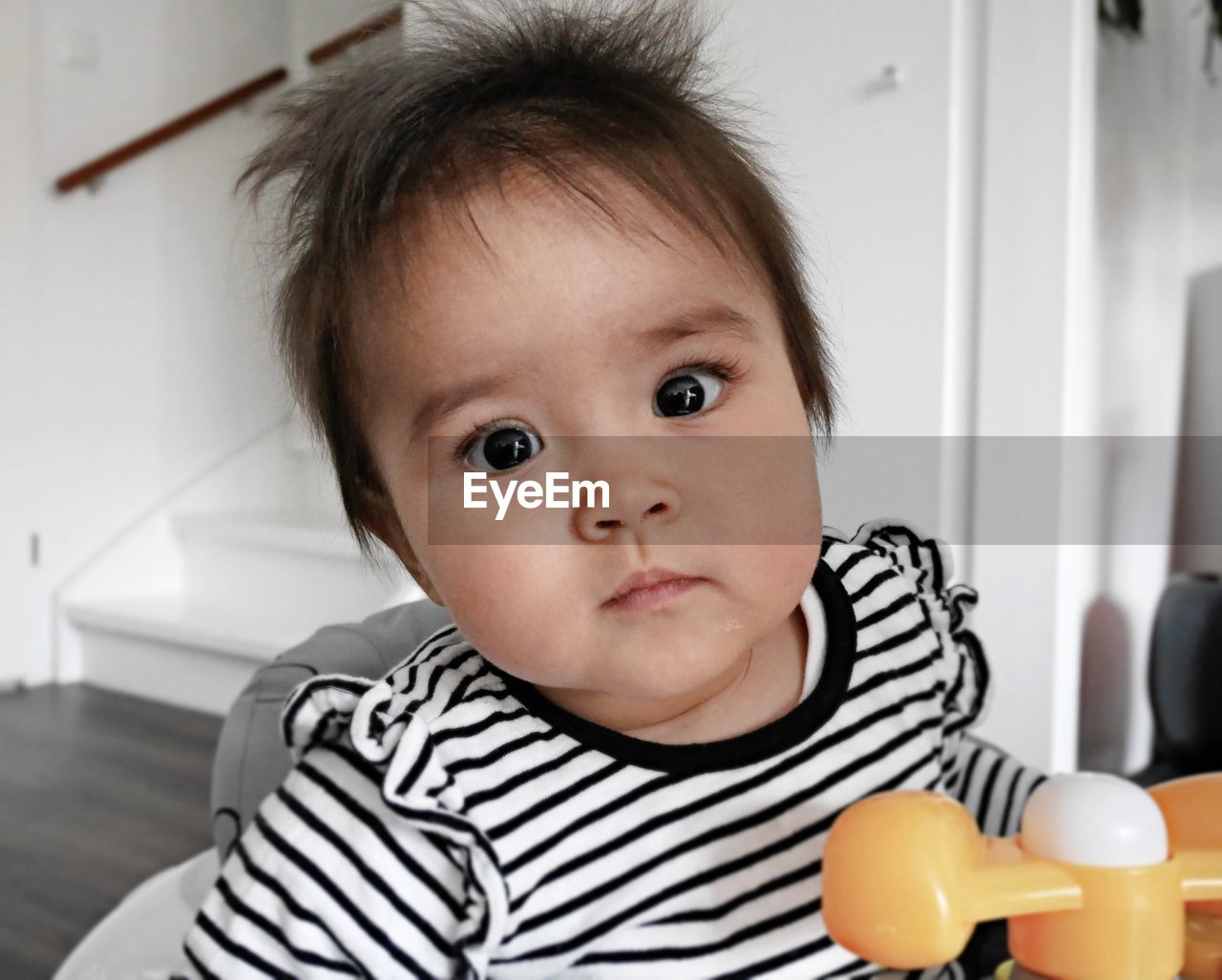 Close-up portrait of cute baby girl sitting at home