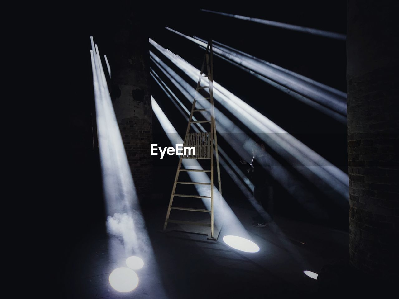 Sunbeam falling on man standing by ladder in room