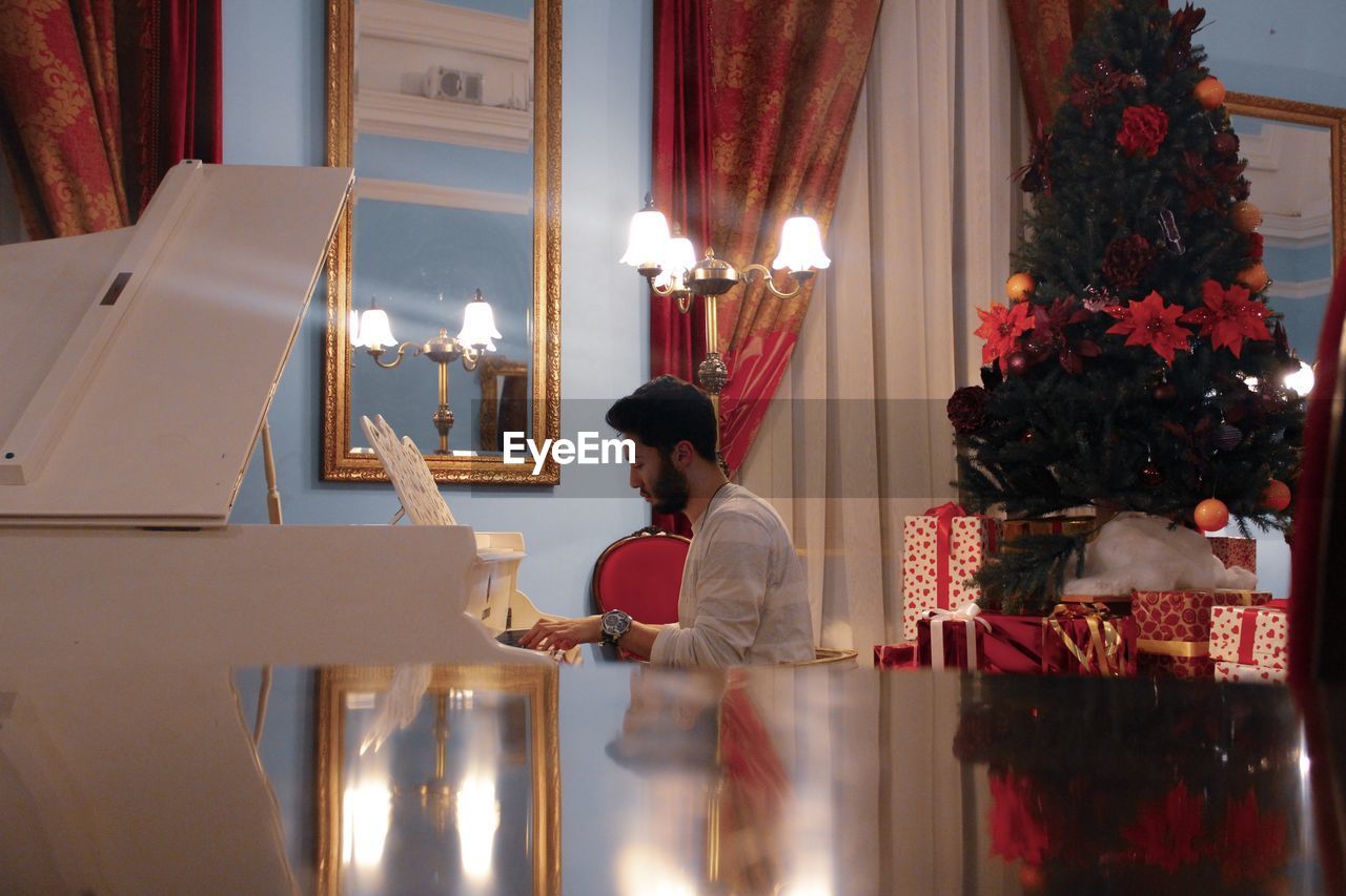 Side view of man playing piano at home