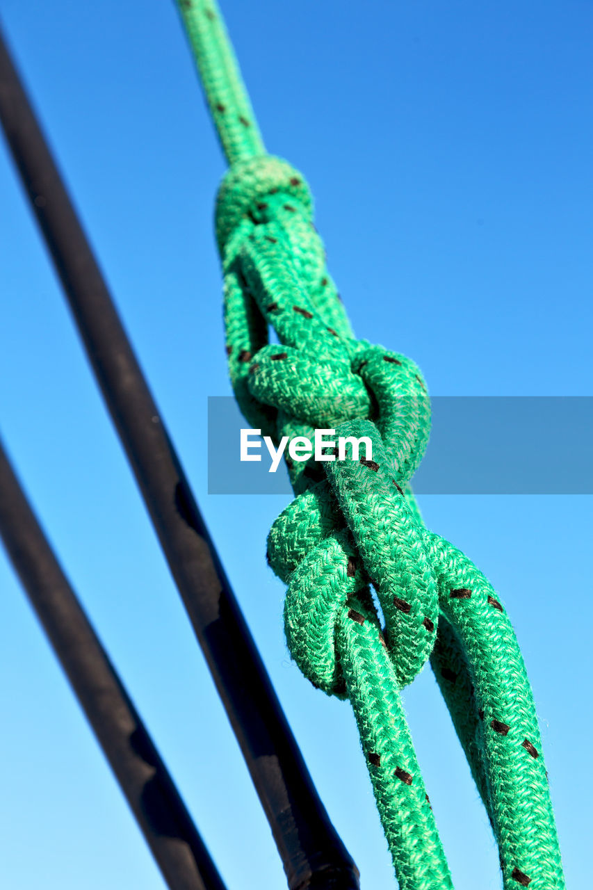 LOW ANGLE VIEW OF ROPE TIED UP ON METAL AGAINST SKY