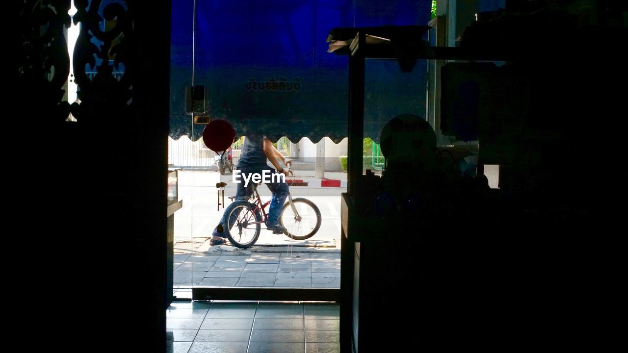 MAN RIDING BICYCLE ON WINDOW