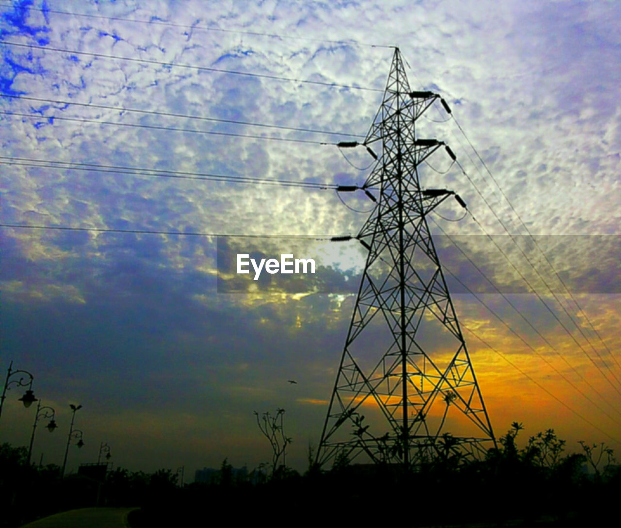 SILHOUETTE OF POWER LINES AGAINST CLOUDY SKY