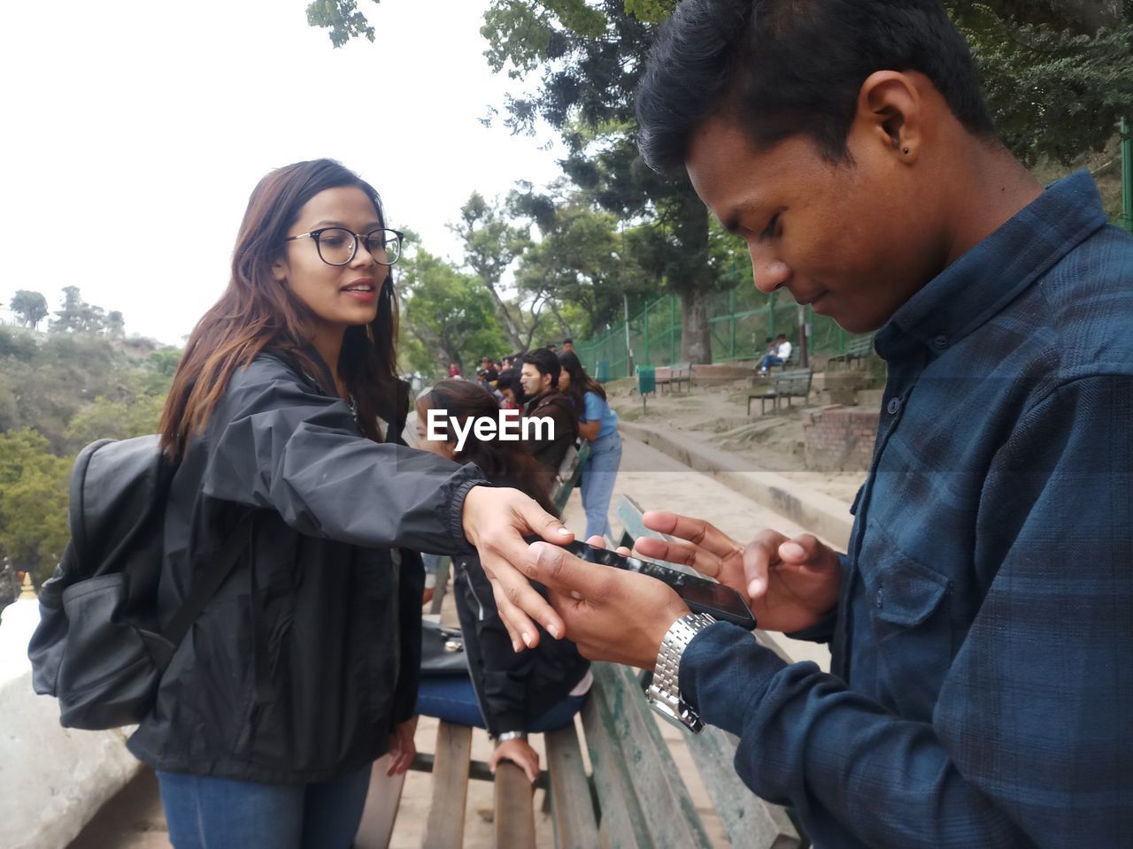 YOUNG MAN HOLDING SMART PHONE WHILE STANDING ON MOBILE