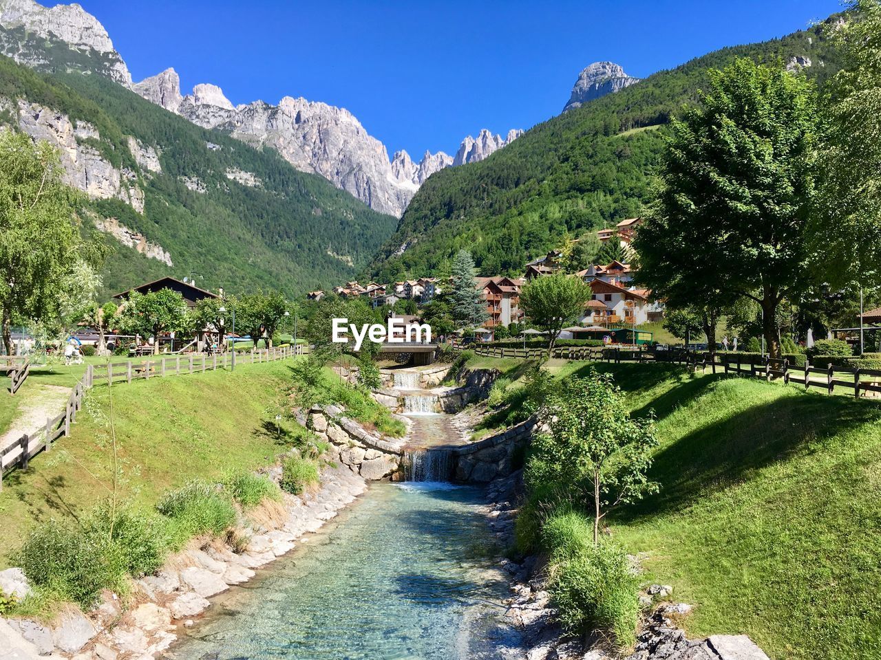 Scenic view of river amidst trees and buildings against sky