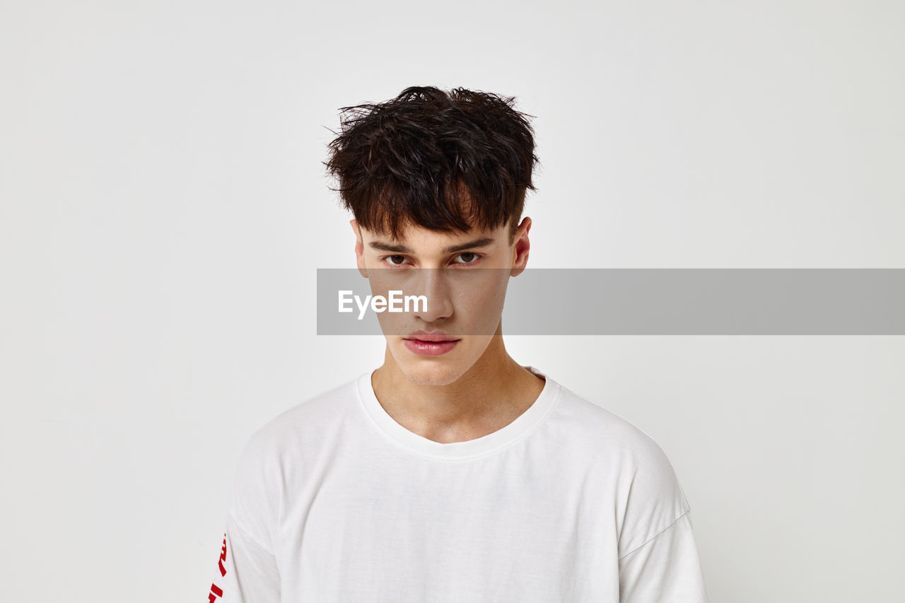 Portrait of young man standing against white background