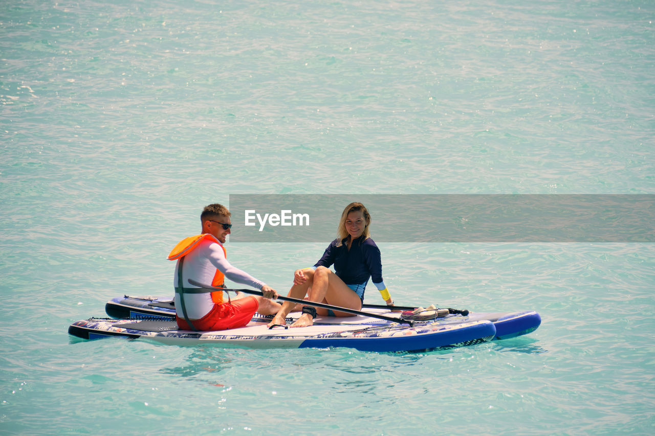 Man and woman sitting on a stand up paddle boards. couple taking time together relaxing on sup board
