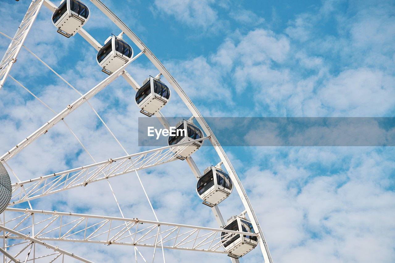 Ferris wheel rotates against background of blue cloudy sky. amusement park attraction