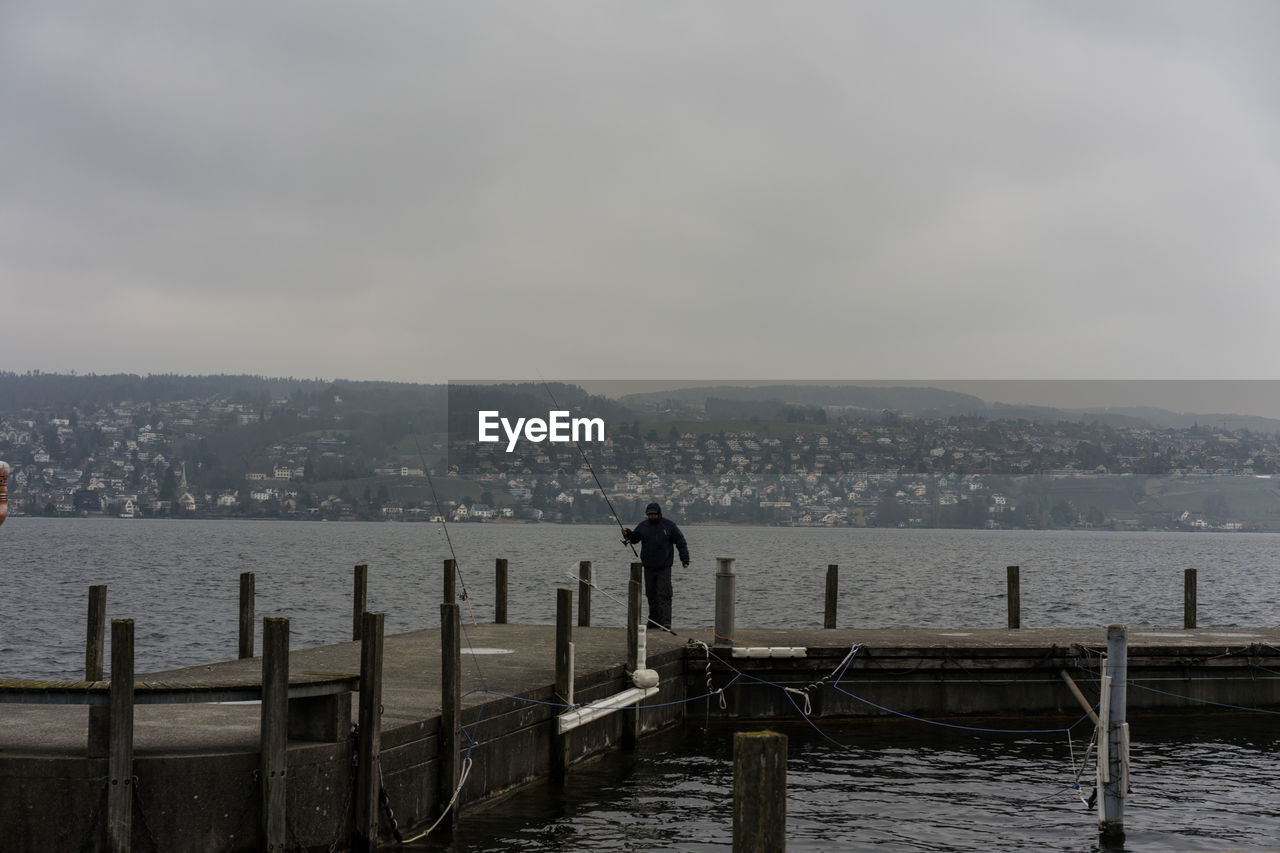 PEOPLE LOOKING AT SEA AGAINST SKY