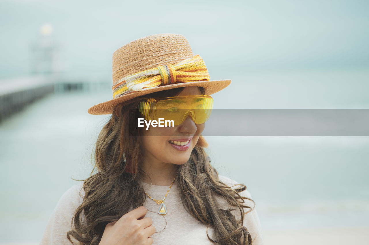 Smiling woman wearing sunglasses while standing against blurred background