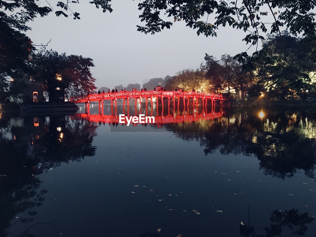 Illuminated bridge over lake against sky at night