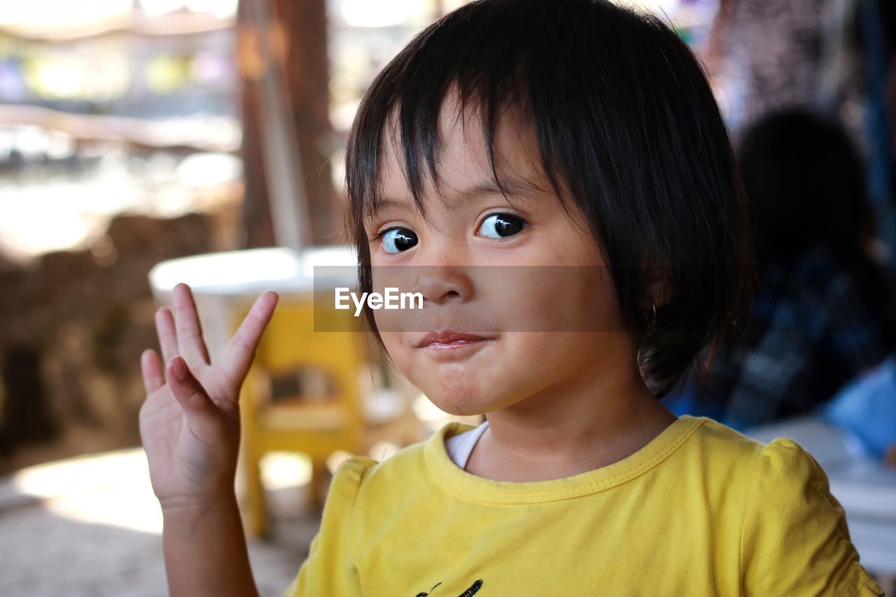 Close-up portrait of cute girl gesturing outdoors