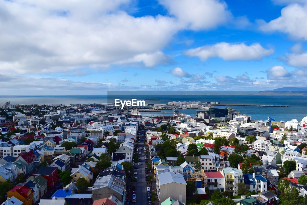 Aerial view of cityscape by sea against sky