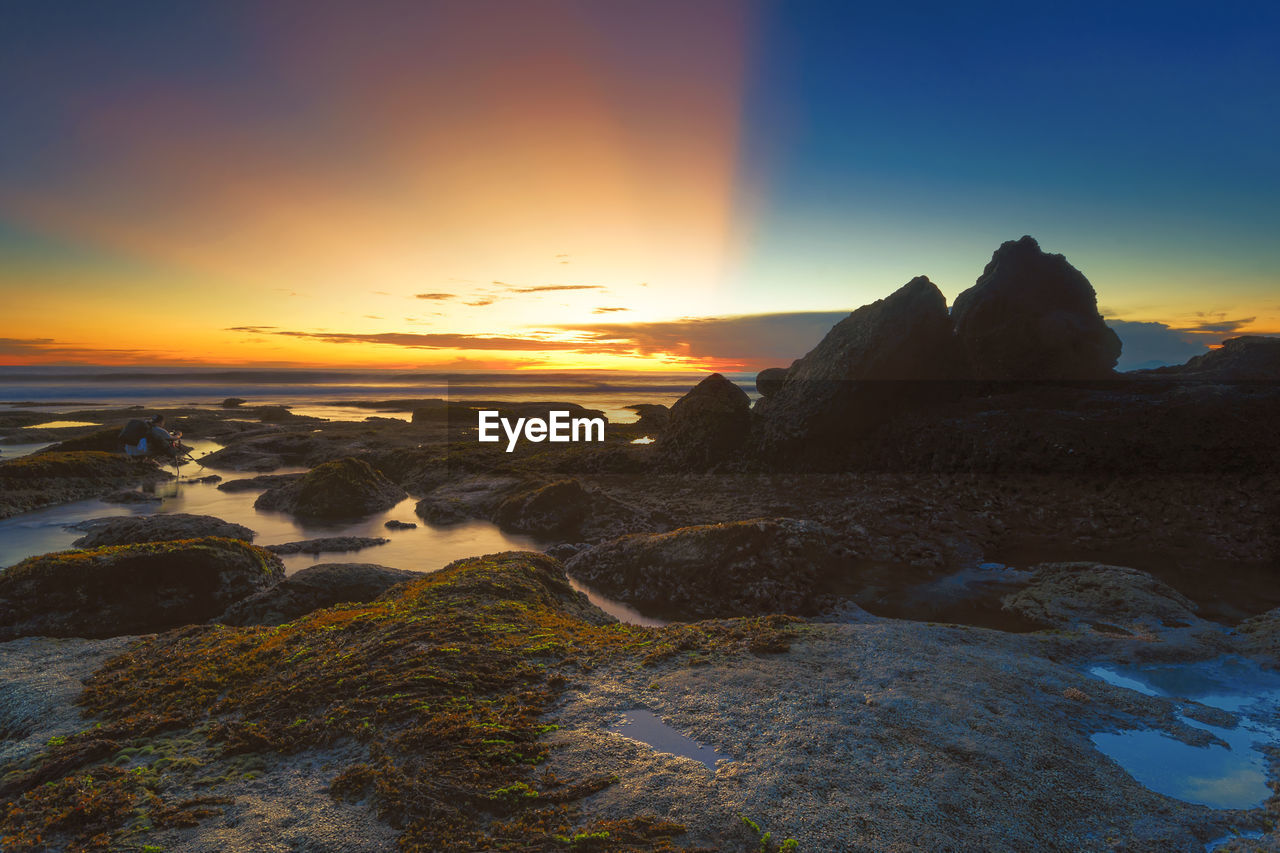 SCENIC VIEW OF BEACH AGAINST SKY AT SUNSET