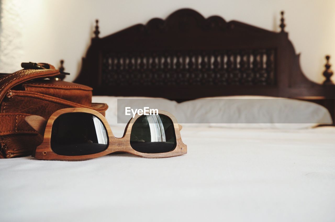 Sunglasses with shoulder bag on bed
