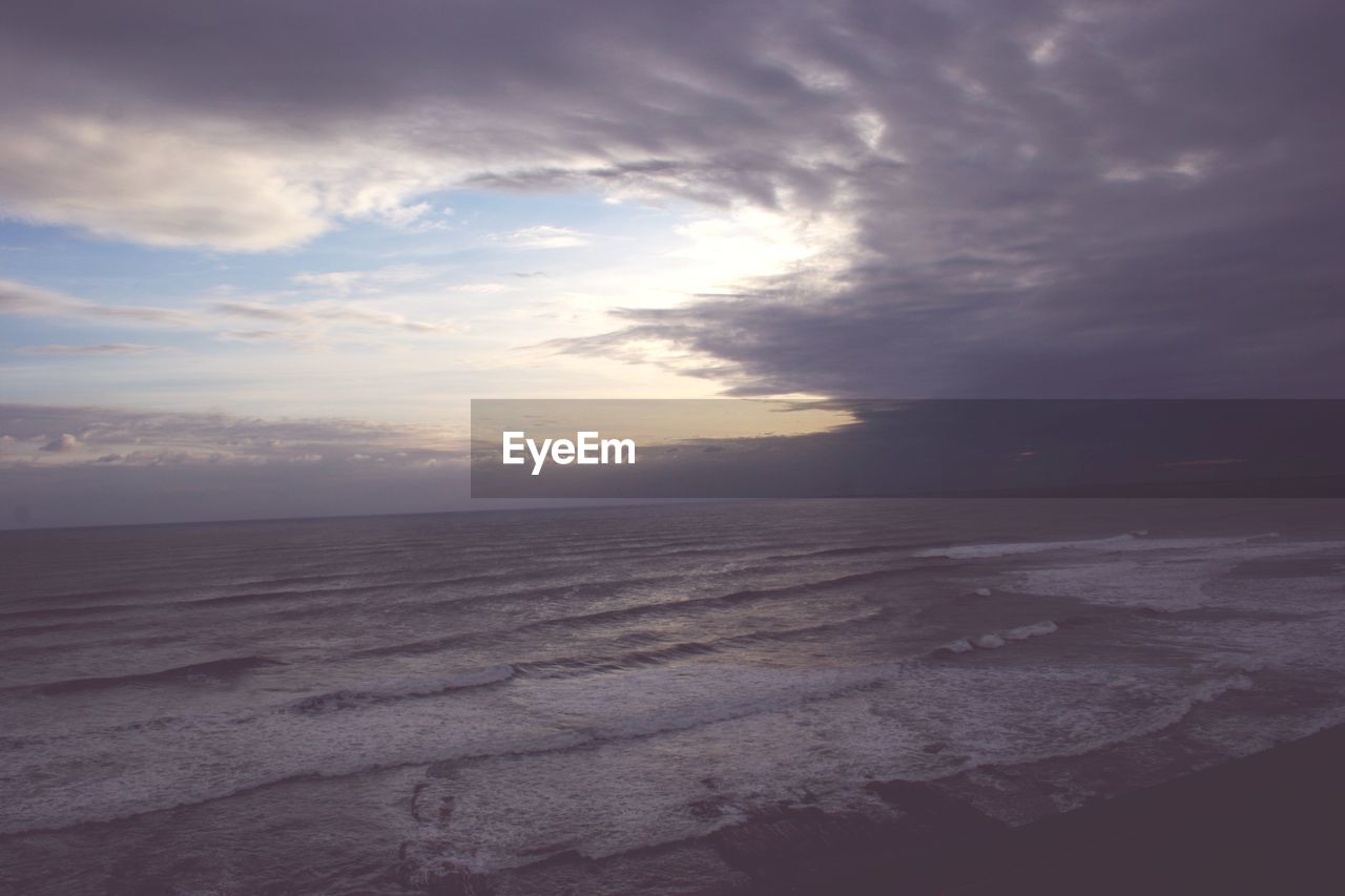 SCENIC VIEW OF BEACH AGAINST SKY AT SUNSET