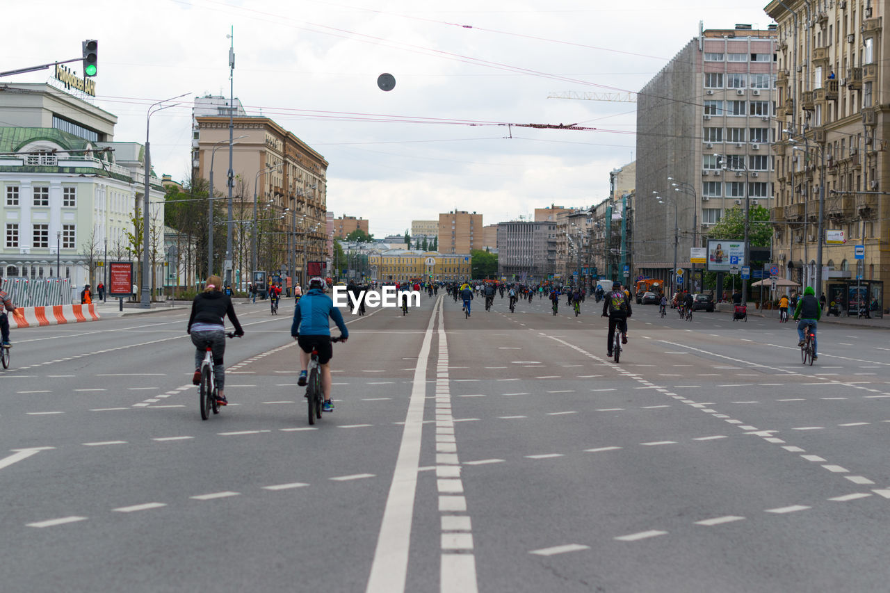 PEOPLE WALKING ON ROAD AGAINST BUILDINGS