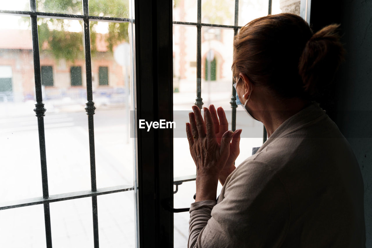 WOMAN LOOKING THROUGH WINDOW